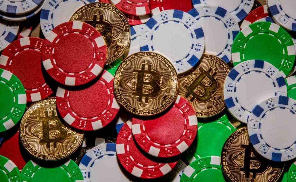 Coins representing physical Bitcoins lie in and among casino chips.
