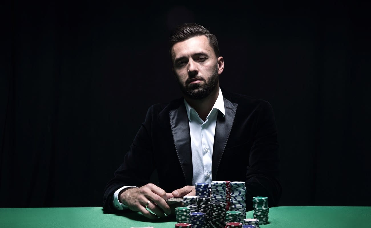 A businessman sitting at a poker table with a large stack of chips in front of him.