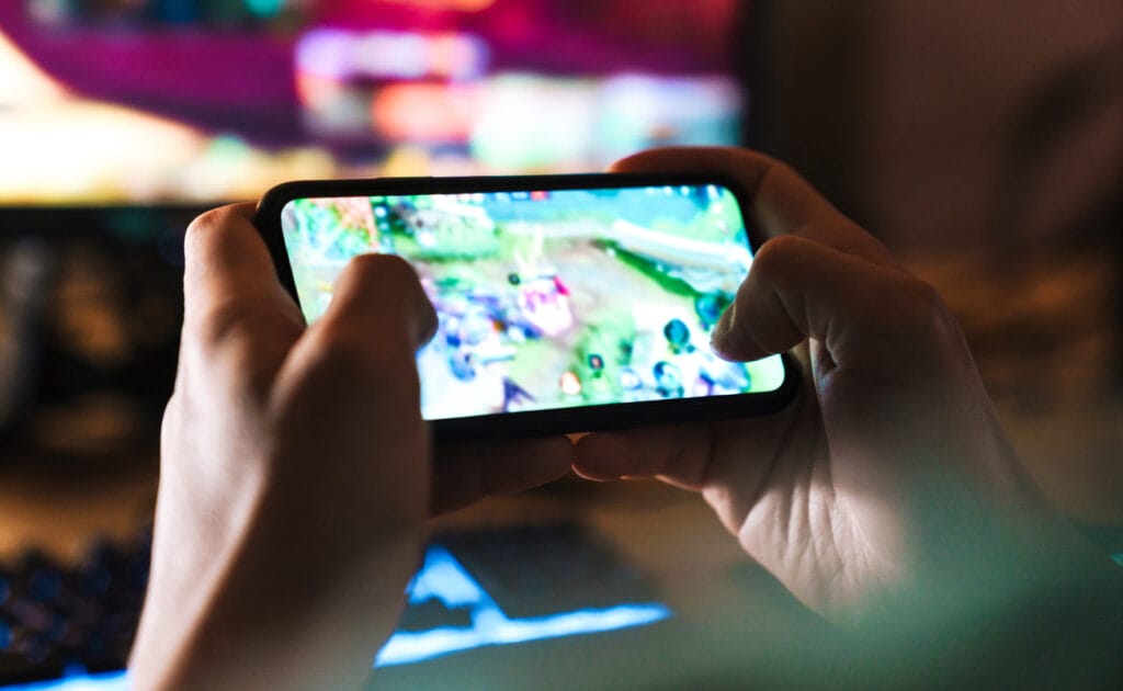 Close-up of a man’s hands playing an online casino game on his mobile phone.