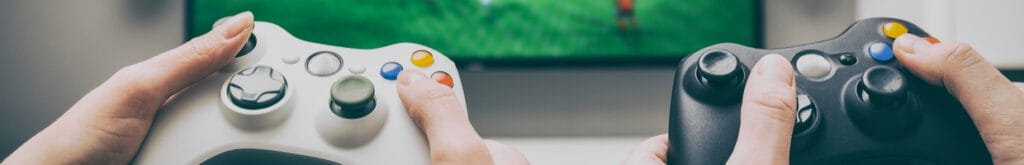 Hands of a man and woman using game controllers with a TV screen in the background.