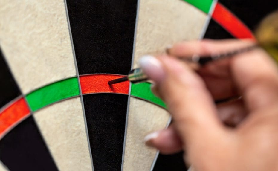 A woman removes a dart from a dartboard.