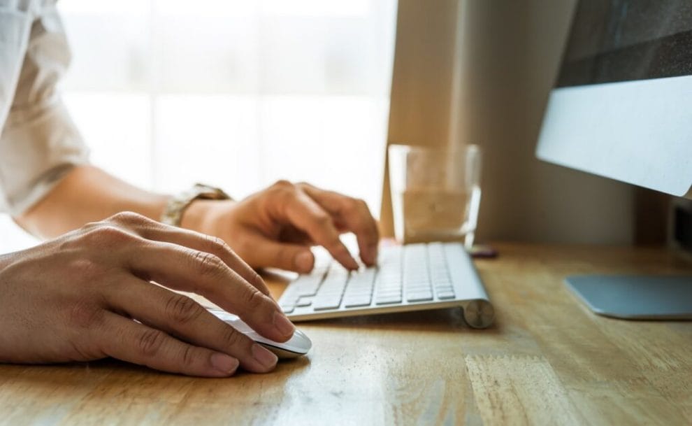 Close-up of a man using a desktop computer.