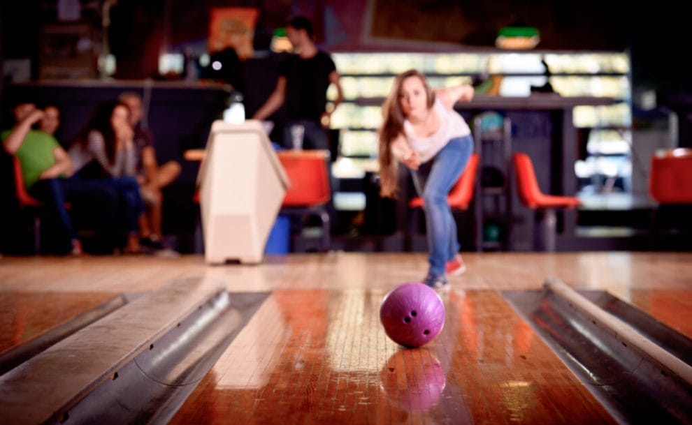 A woman bowls a standard bowling ball down a lane.