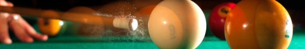 A player hits the white ball with the cue stick.