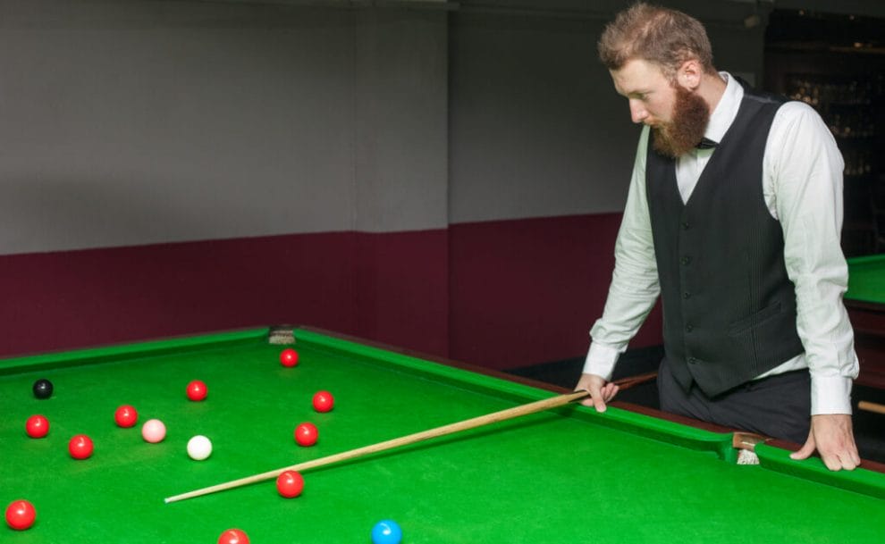 A snooker player looking at the balls and thinking.