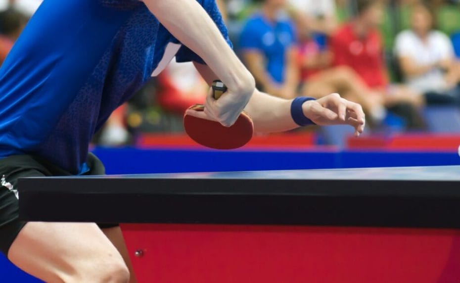 An athlete preparing to hit a table tennis ball with a racket.