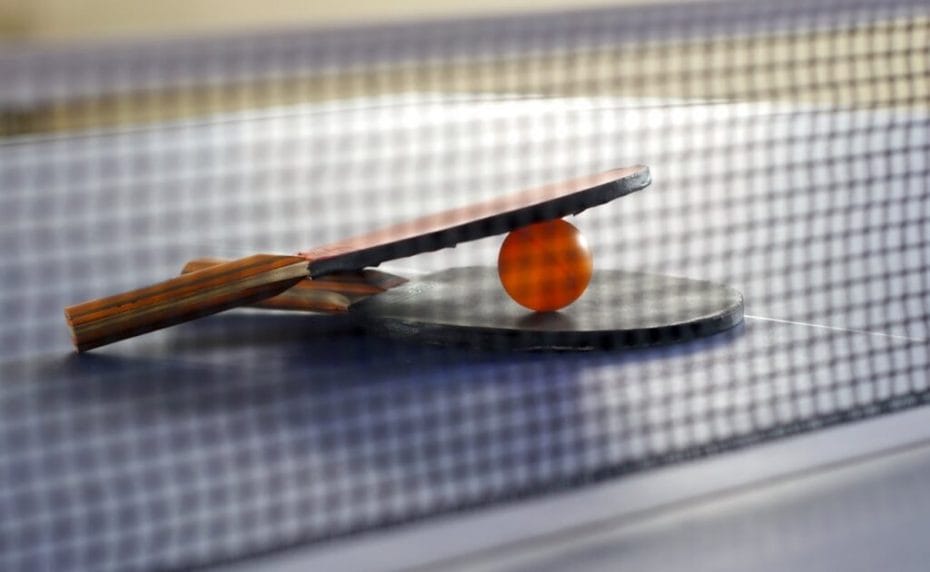 Close-up of two table tennis rackets and a ball on a game table.