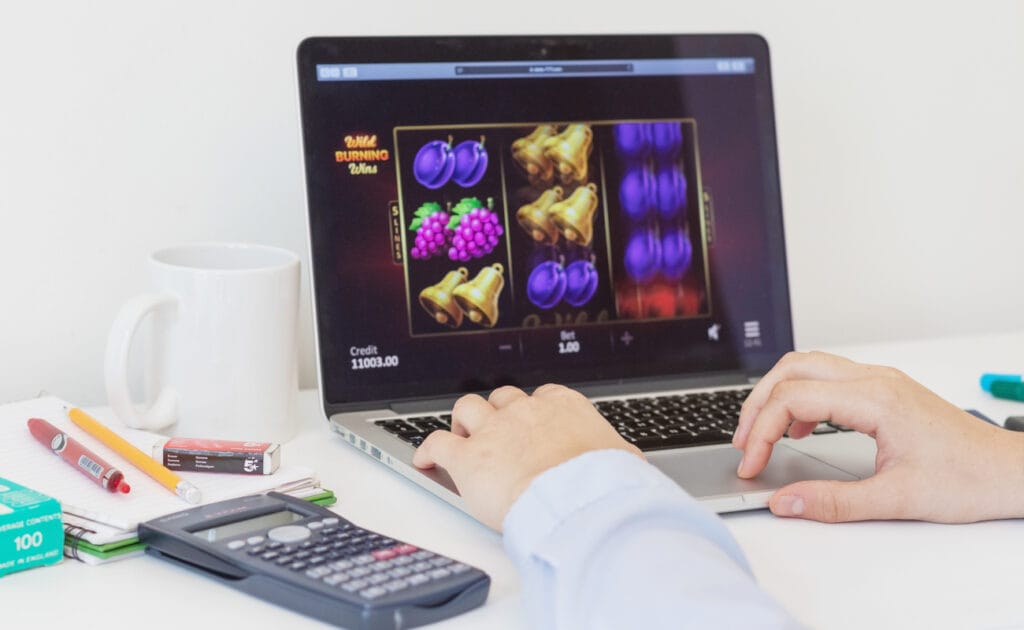 A man plays an online slot game on a laptop computer.