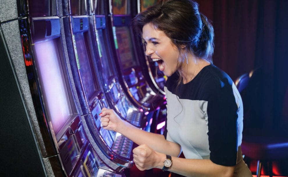 Happy woman wins at a casino slot machine.