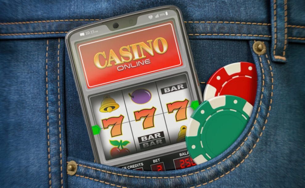 Gambling chips and a mobile phone sticking out of a jeans’ pocket, showing an online slot reel and three ‘7s’.