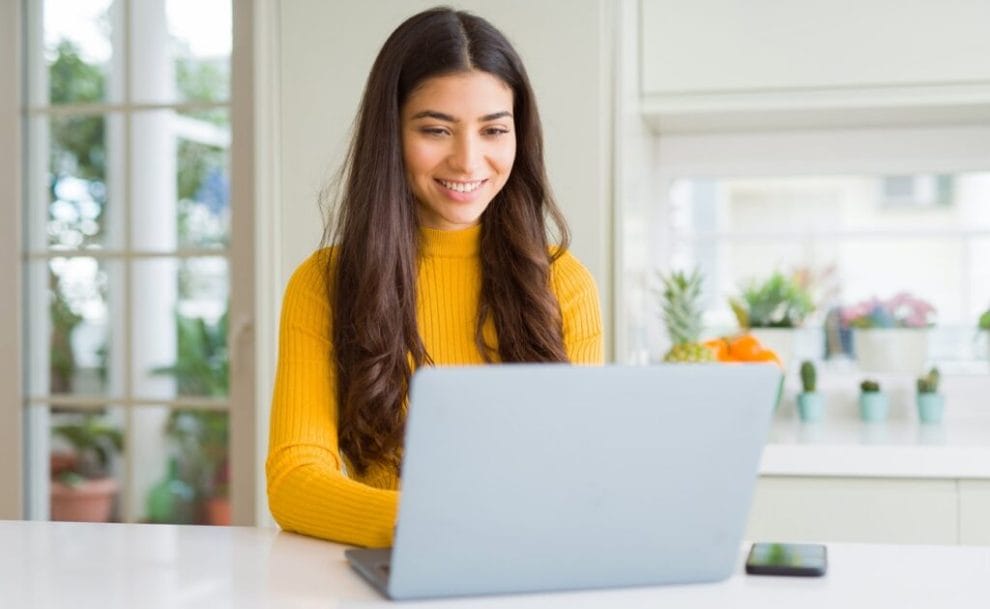 A woman smiles while making her own bingo cards at her computer.