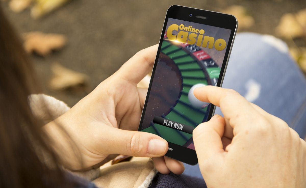 Close-up of a woman logging onto an online casino site on her mobile phone.