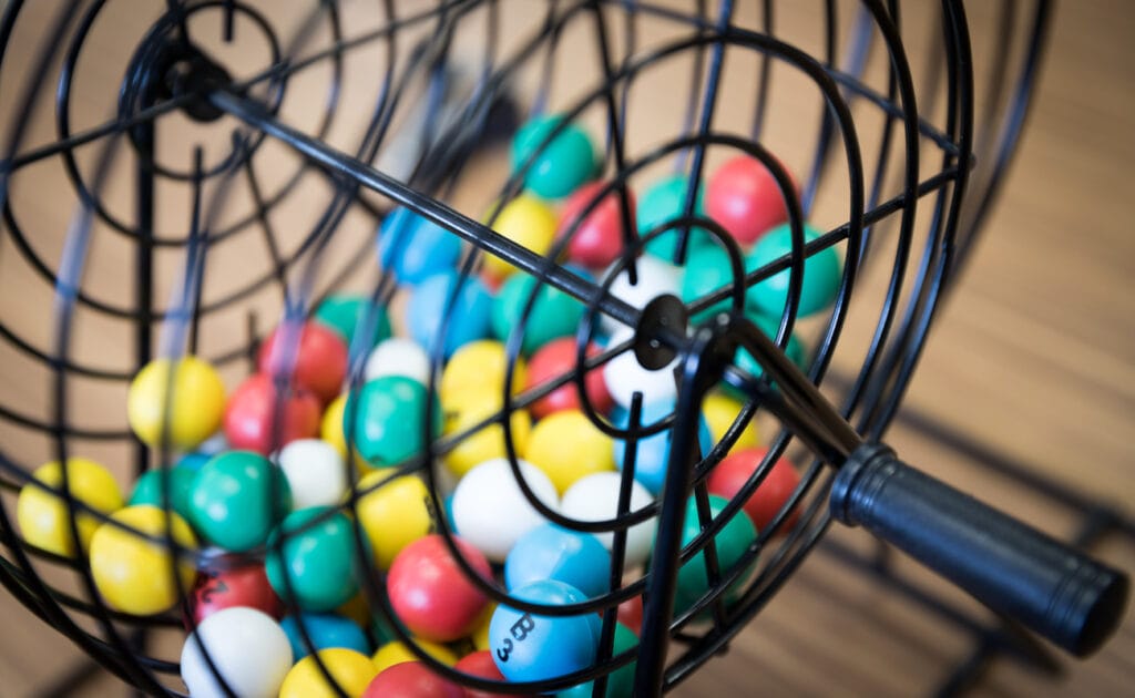 Brightly colored bingo balls in a black cage.