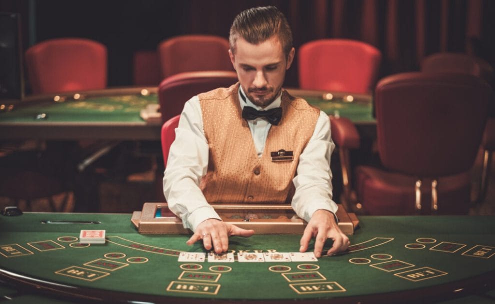 A croupier sits at a card game table.