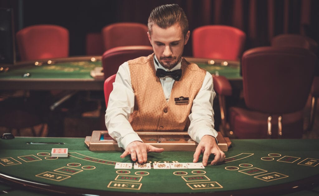 A croupier sits at a card game table.