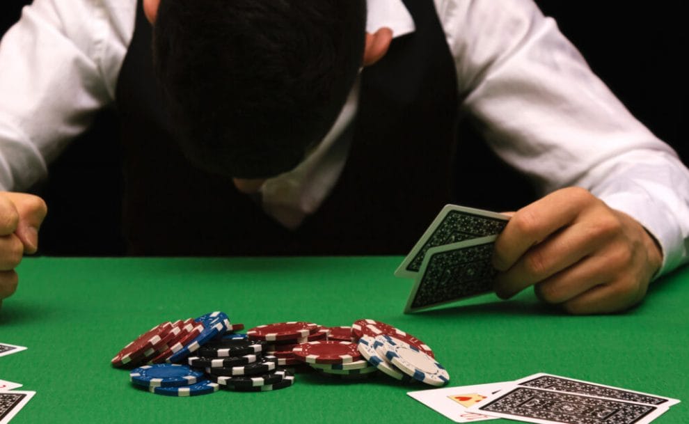 A man with his head lowered at a casino table.