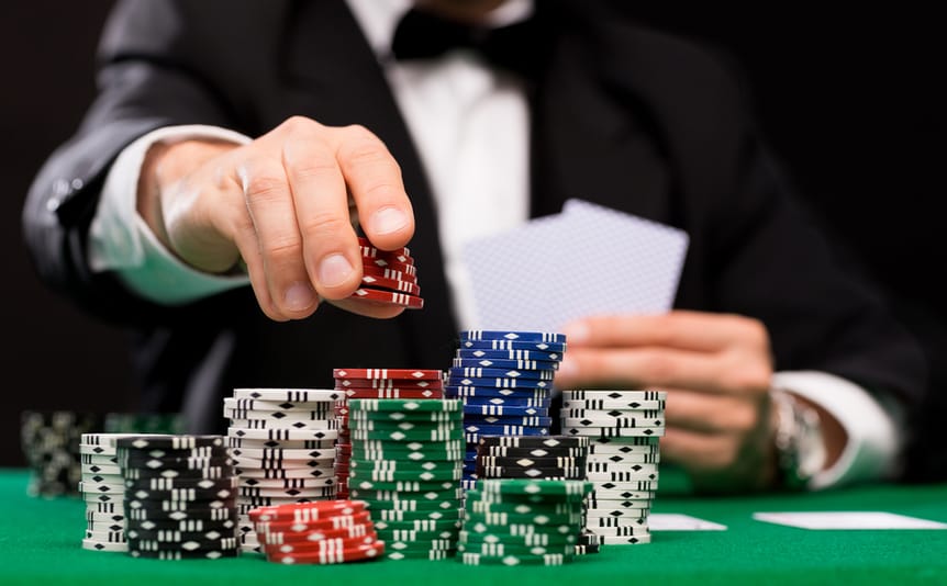 Poker chips on a table with a man sitting in the background.