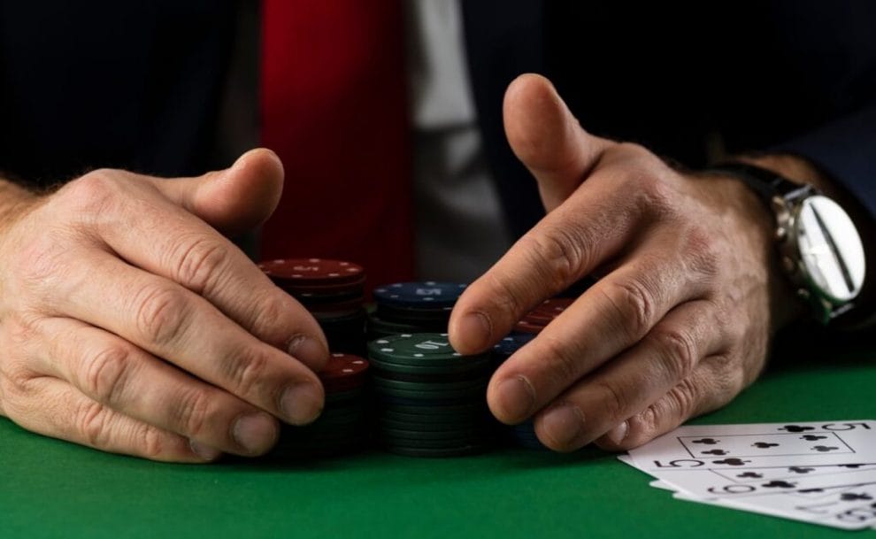 Man putting his hands around stacks of chips at a casino poker table.