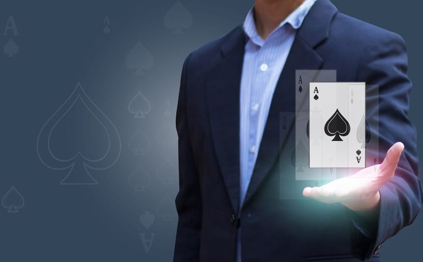 Man in business suit with a lit-up ace of spades card hovering above his palm.