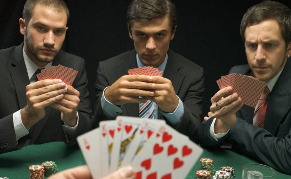A group of men in suits play poker.