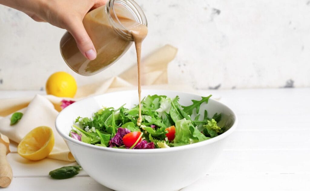 Salad dressing is drizzled over a salad.