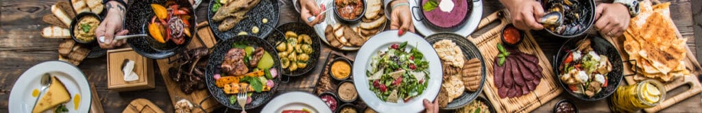 A top view of a table laden with food that has mostly been grilled.