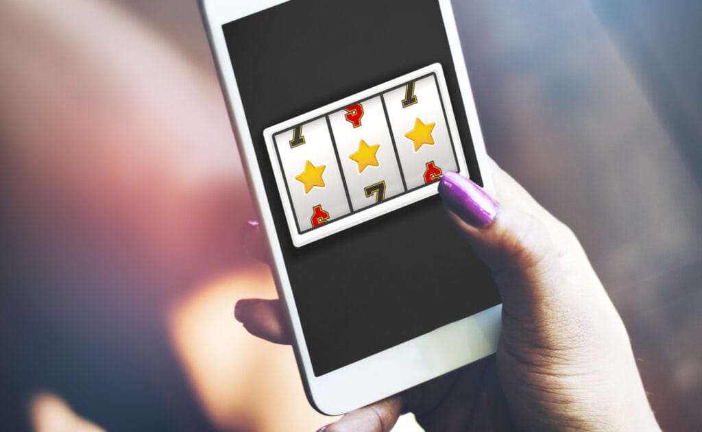 A woman plays online slots on a smartphone.