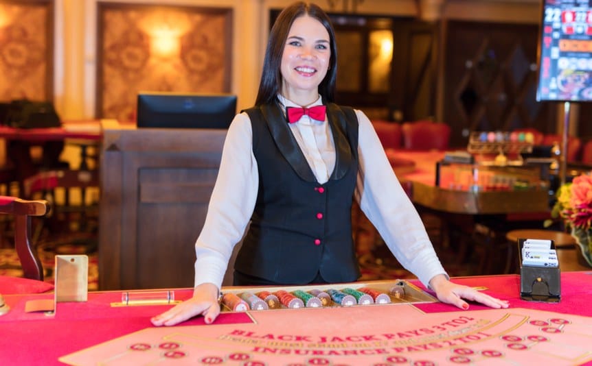 A friendly female casino dealer smiles.