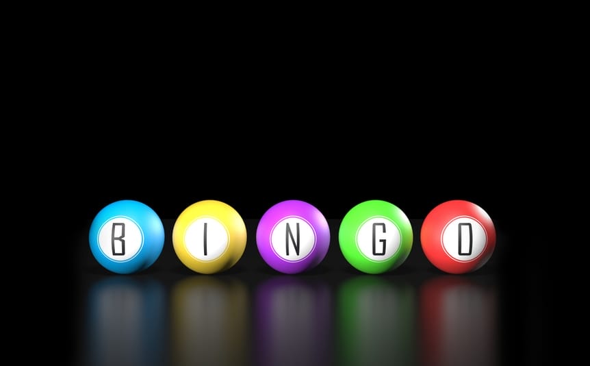 Colorful bingo balls spelling out the word bingo on a reflective black surface