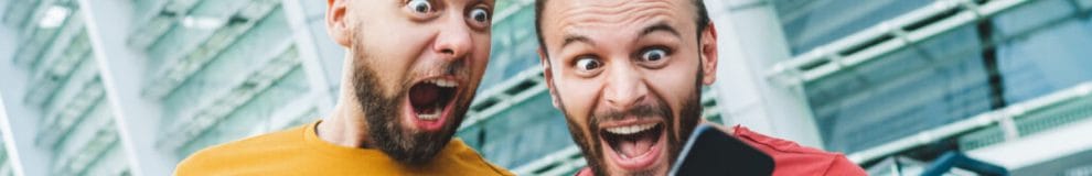 Two excited men looking at a phone shouting and celebrating.