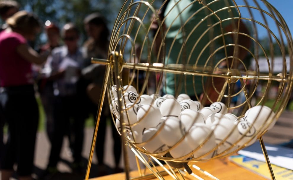 White bingo balls in a gold cage on a table outside.