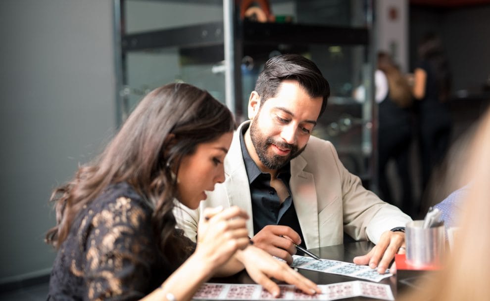 A man and woman mark off numbers on their bingo cards.