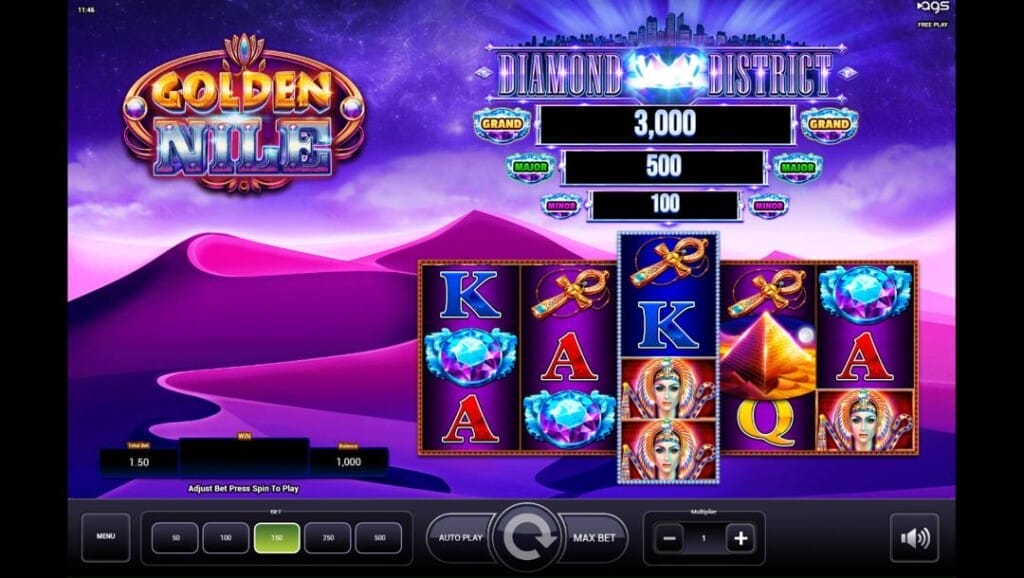 A screenshot of the Golden Nile slot reels. The background is made up of purple and pink sand dunes. The reels in the foreground have various Egyptian- and playing-card-themed slot symbols, as well as three jackpots visible above the reels.