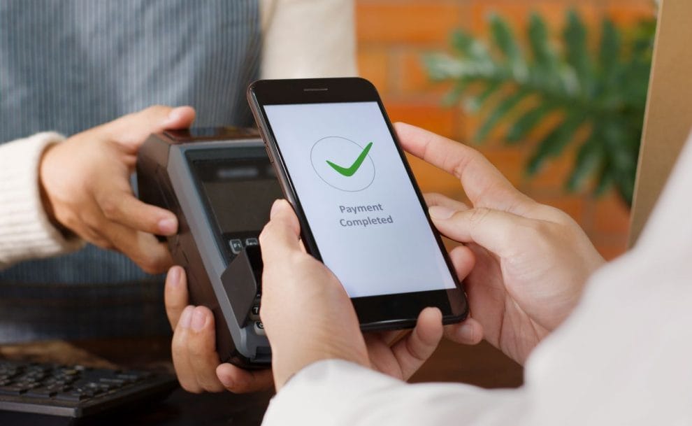 Person using their mobile phone to make a payment on a card machine.