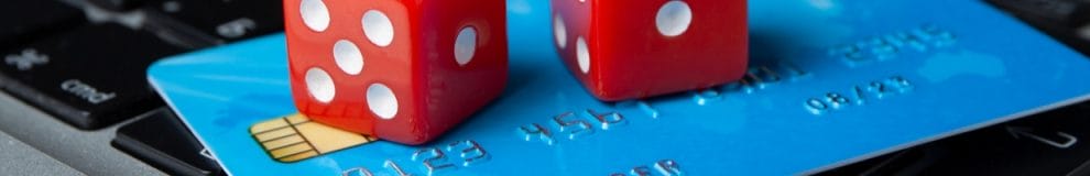 Two red-and-white dice rest on a credit card on top of a laptop keyboard.