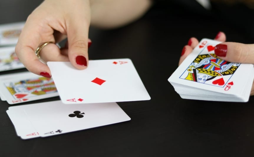 A woman arranging playing cards on a black table.