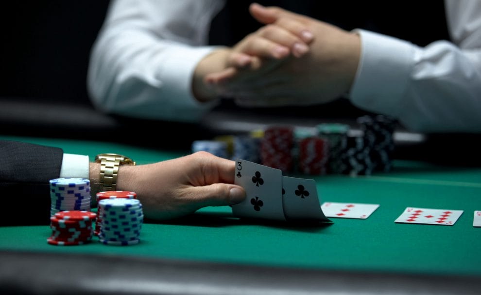 A poker player lifts up a bad hand with the croupier sitting on the other side of the table.