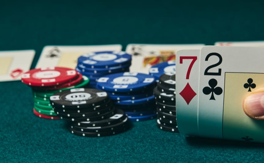 Some poker chips in the background with 7 and 2 cards in the foreground.