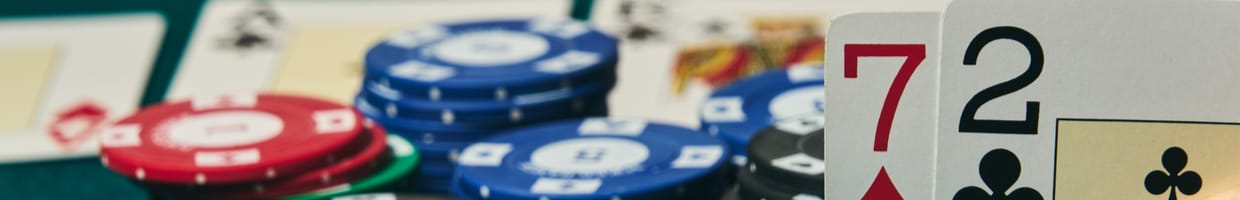 Some poker chips in the background with 7 and 2 cards in the foreground.