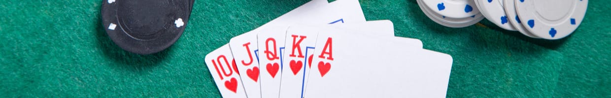 Computer keyboard on a green felt table with casino chips and playing cards around and on top of it.