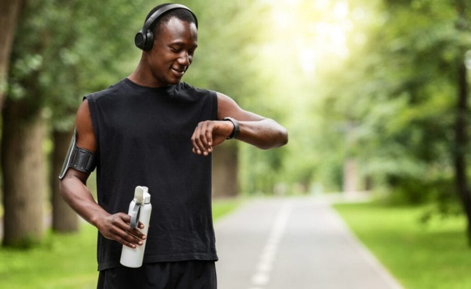 A young man stops during a run to check his smartwatch.