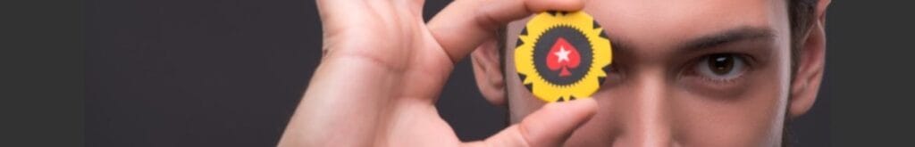 A man holding a black and yellow casino chip in front of his eye