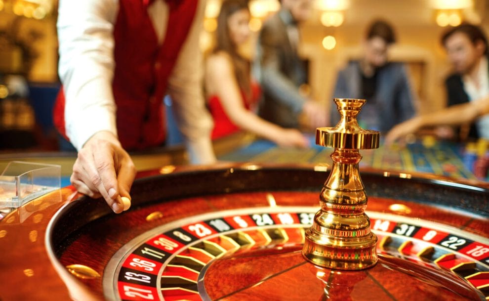 A croupier holds the ball above the roulette wheel.