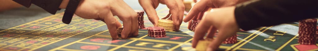 A close-up of people placing chips on a roulette table.