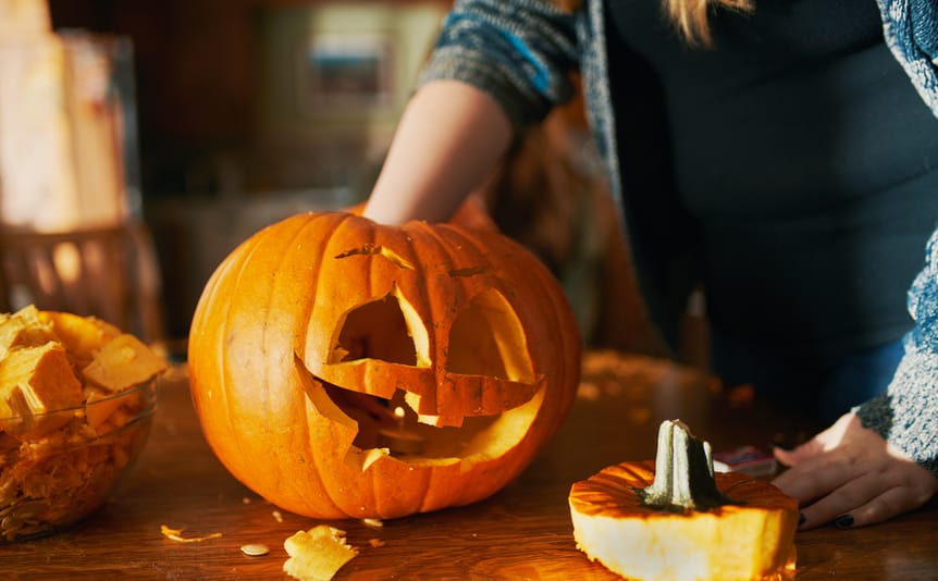 A woman carves a fall pumpkin.