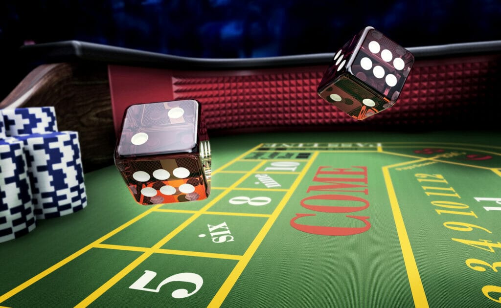 Dice bounce across a craps table with stacks of casino chips to one side.
