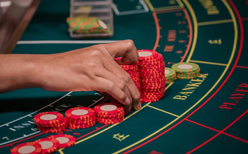 A dealer organizing chips on a baccarat table.