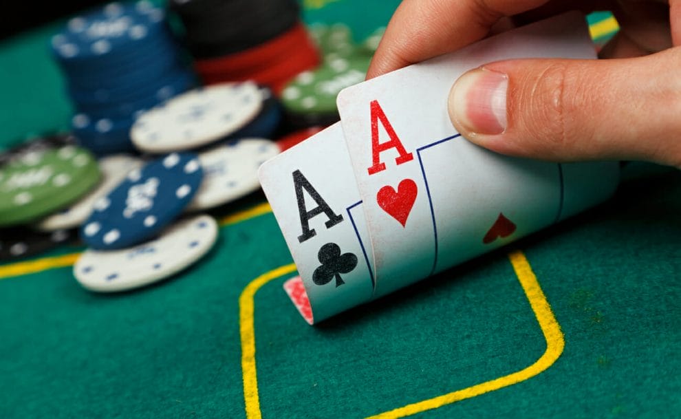 A player views his hole cards at the felt table – a pair of aces.