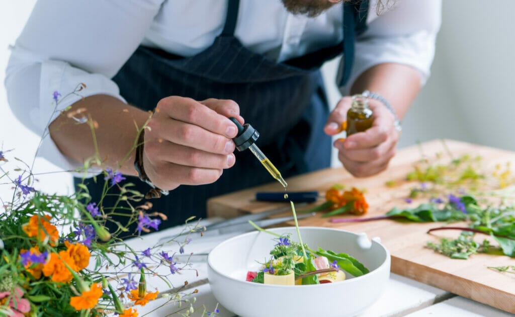 A chef dropping oils onto a salad from a dropper.
