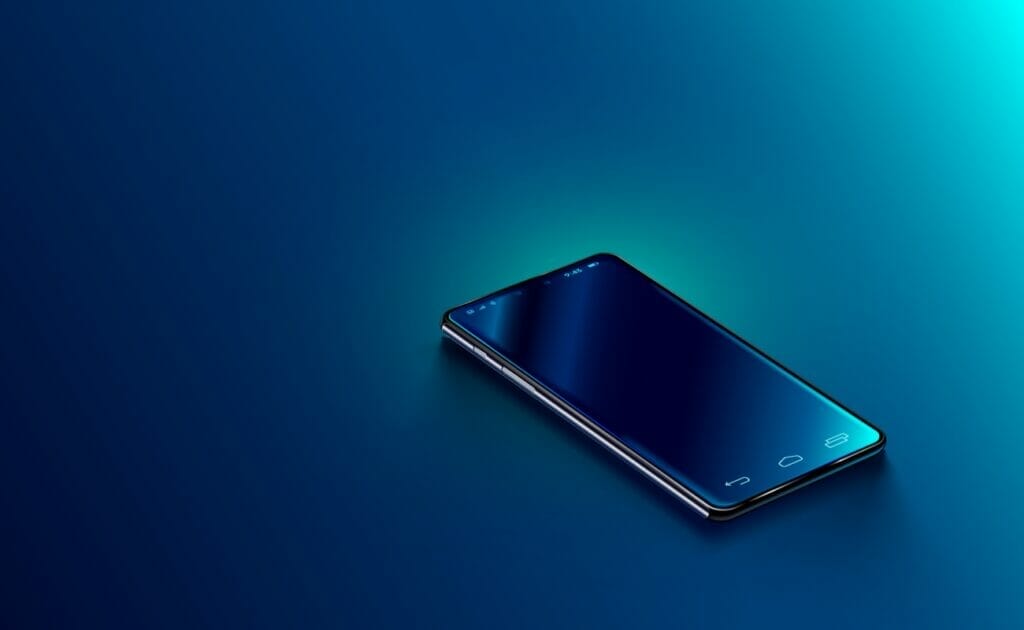 A modern black smartphone against a dark blue desk.